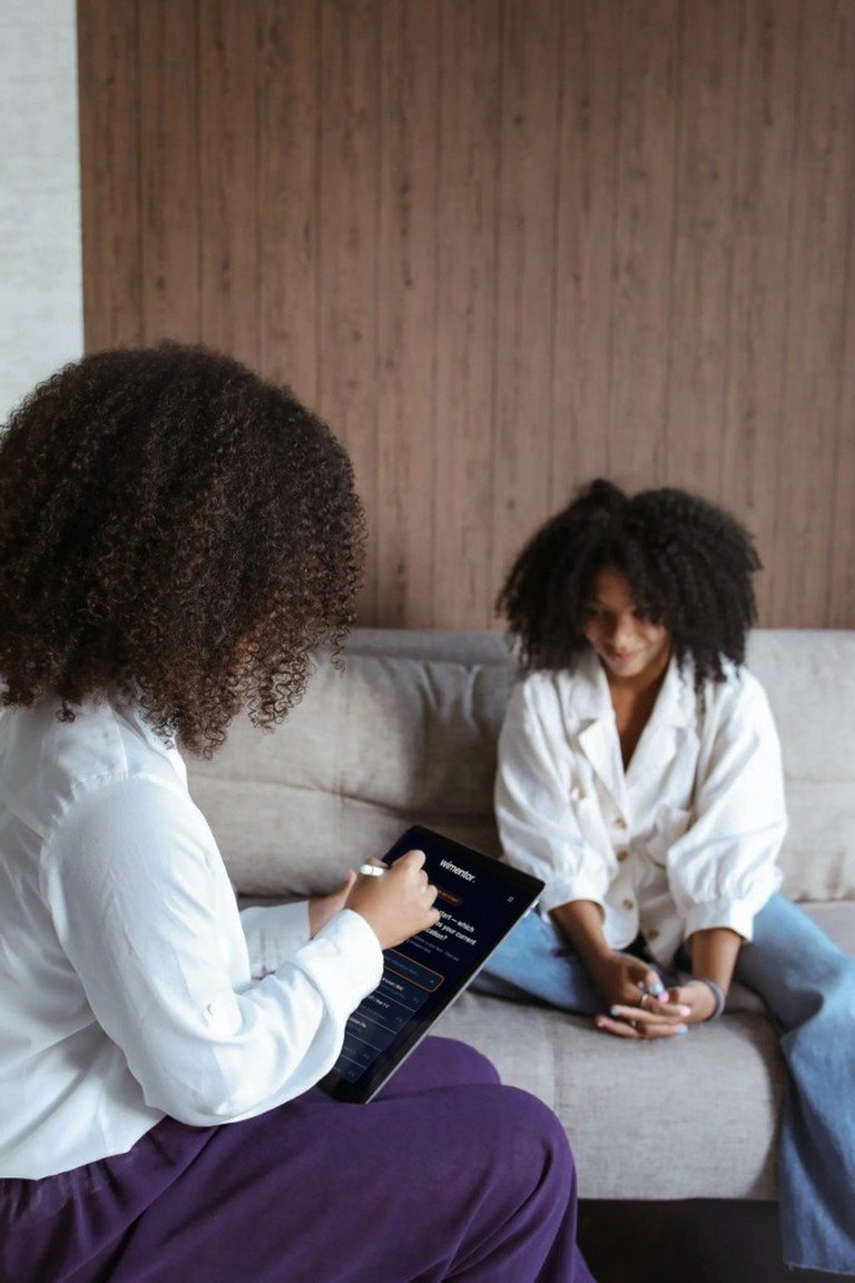 A mentor sitting with a student, holding a tablet that shows the first question of the Wimentor career assessment